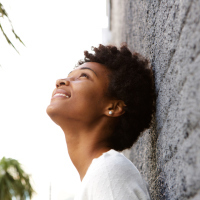 woman leaning against a wall, looking up and smiling