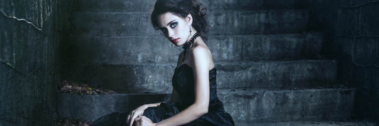 woman in black dress sitting on concrete stairs