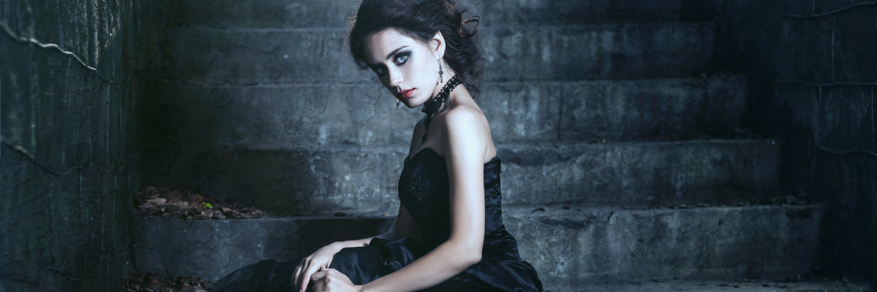 Sensory Overload: Feeling Like a Vampire After Traumatic Brain Injury woman in black dress sitting on concrete stairs