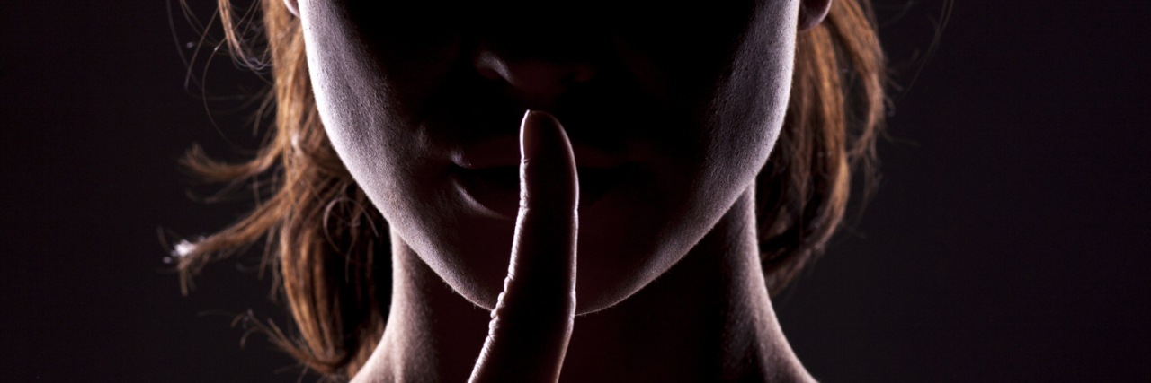 silhouette of a woman holding her finger in front of her lips as shhh