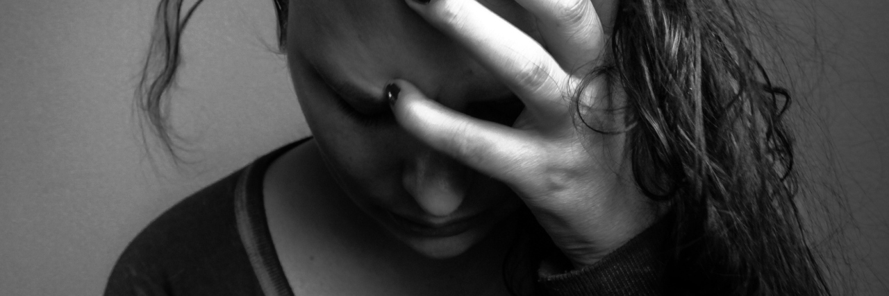 What I Wish People Knew About My Depression black and white photo of depressed young woman holding head with hands in hair and looking down