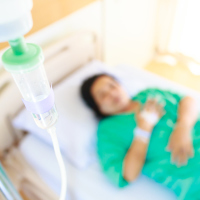 A woman in a hospital bed, focused on an IV of fluids.