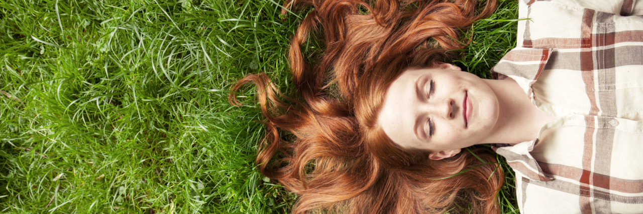 Surviving Spring as a Spoonie in the Southern Hemisphere woman with red hair lying in the grass outside