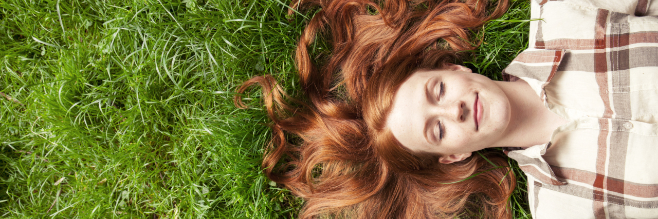woman with red hair lying in the grass outside