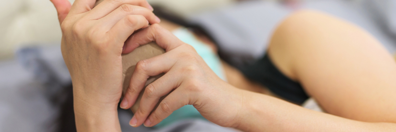 Calling Into Work Because of Exhaustion From Congenital Heart Disease woman on her phone while lying in bed