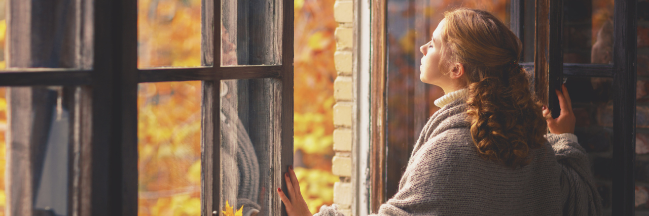 woman looking out her window during autumn