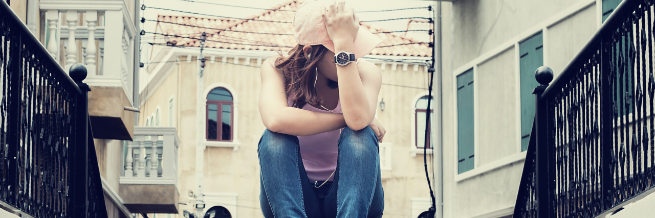 How BPD Makes a Breakup Feel Like the End of the World sad woman sitting alone on steps hiding face looking away
