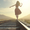 woman walking down a railroad and balancing on the rail