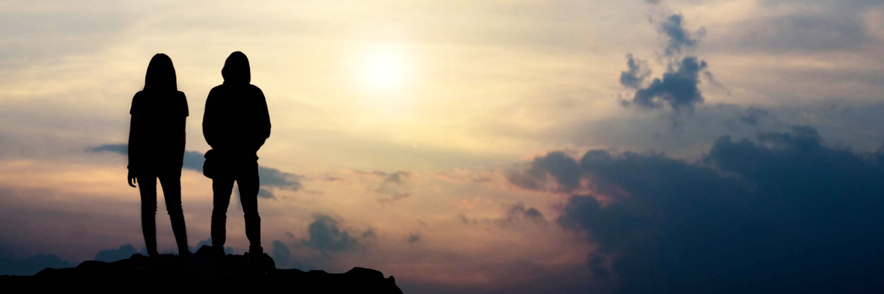 Couple standing on rock at sunset.