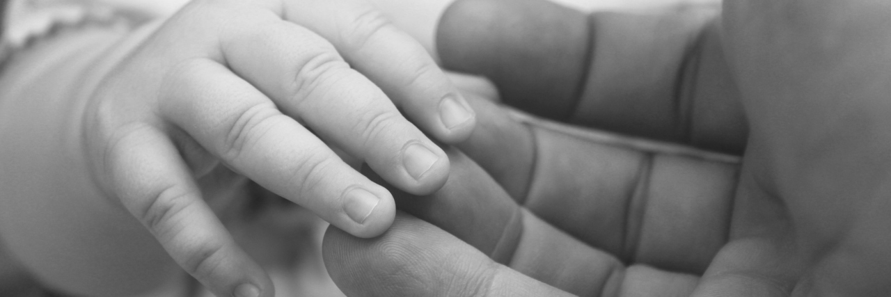 small child's hand in hand of adult parent closeup