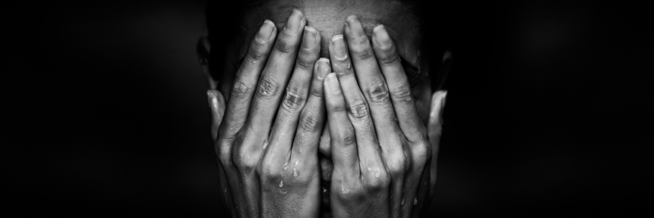 What the Pain of Trigeminal Neuralgia Feels Like black and white photo of woman holding her face in her hands