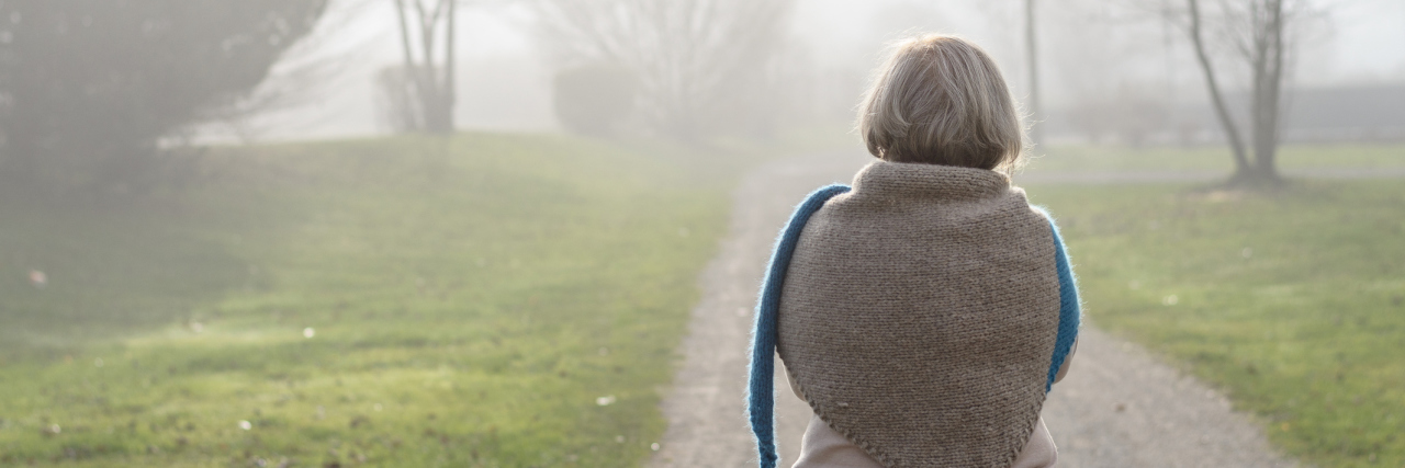 When I Realized I Was Blaming Myself for My Asthma An older woman walking down a pathway in a park.