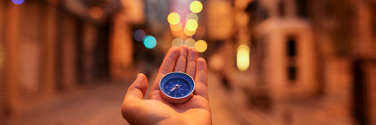 A woman holding a compass with a city in the background.