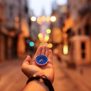A woman holding a compass with a city in the background.