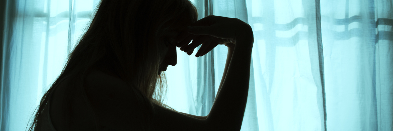 How Stigma Can Affect Support Given to Those With Migraine Silhouette of woman sitting in bed holding her head