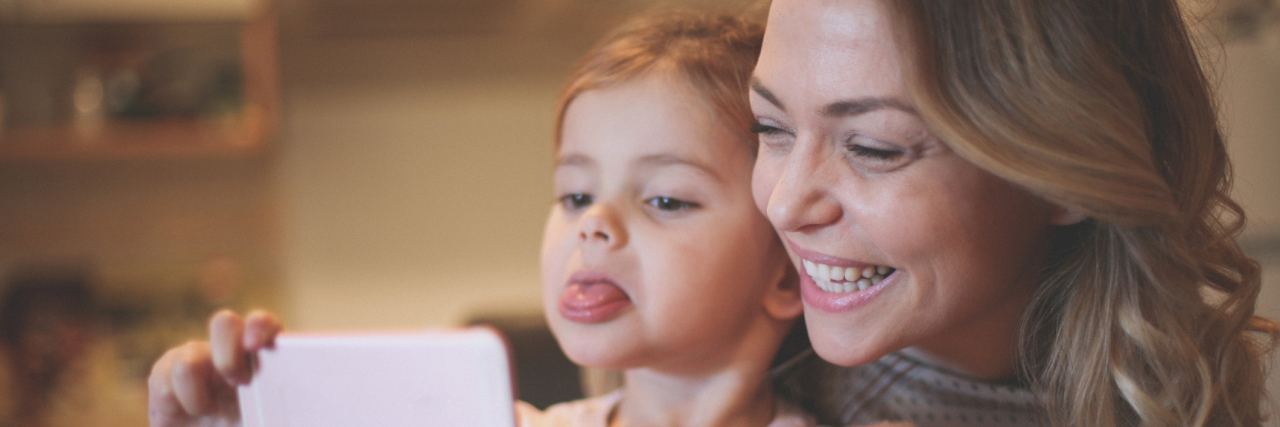 To the Chronically Ill Parents, From a Chronically Ill Daughter A mom and daughter taking a selfie together, the mom smiling and child sticking her tongue out.