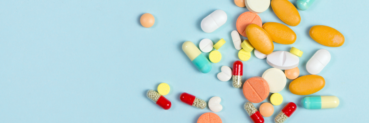 The 6 Medication Side Effects I Experience Treating My Bipolar Assorted pharmaceutical medicine pills, tablets and capsules over blue background
