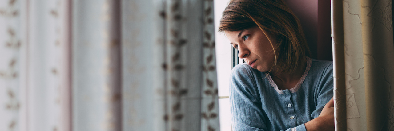 I May Be at a 'Healthy' Weight, but I Still Have Anorexia Young sad woman sitting on the window looking outside