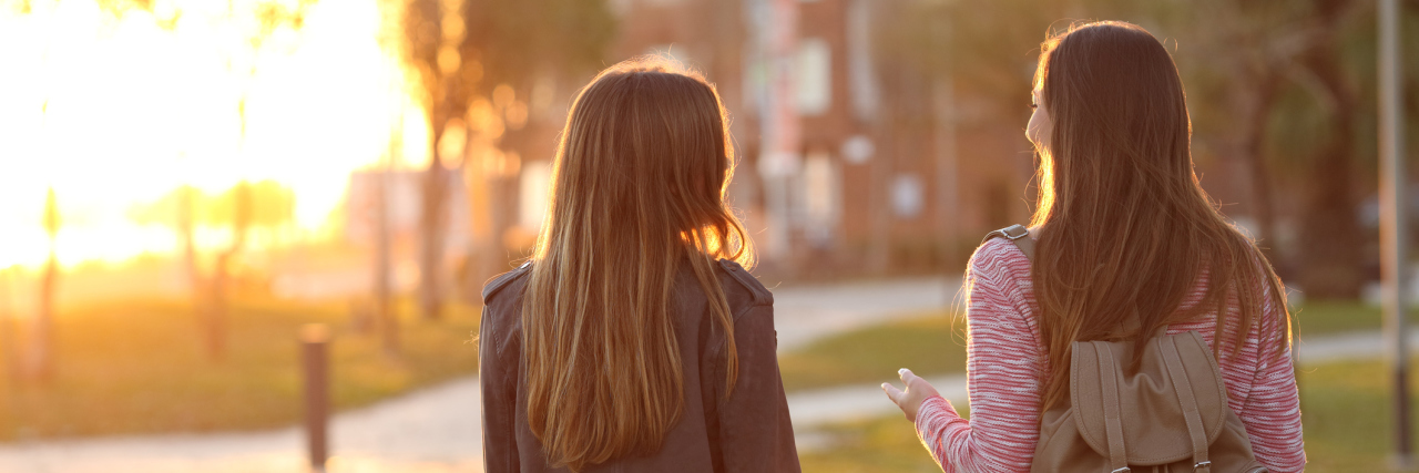 How Chronic Illness Affects Friendship two friends walking outside at sunset
