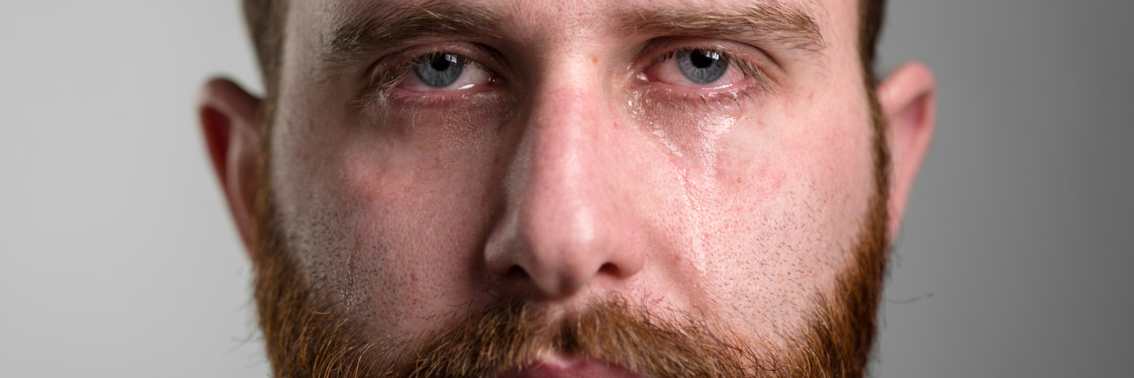 Why Phrases Like 'Man Up' Could Contribute to Male Suicide man with beard looking into camera with tears in eyes