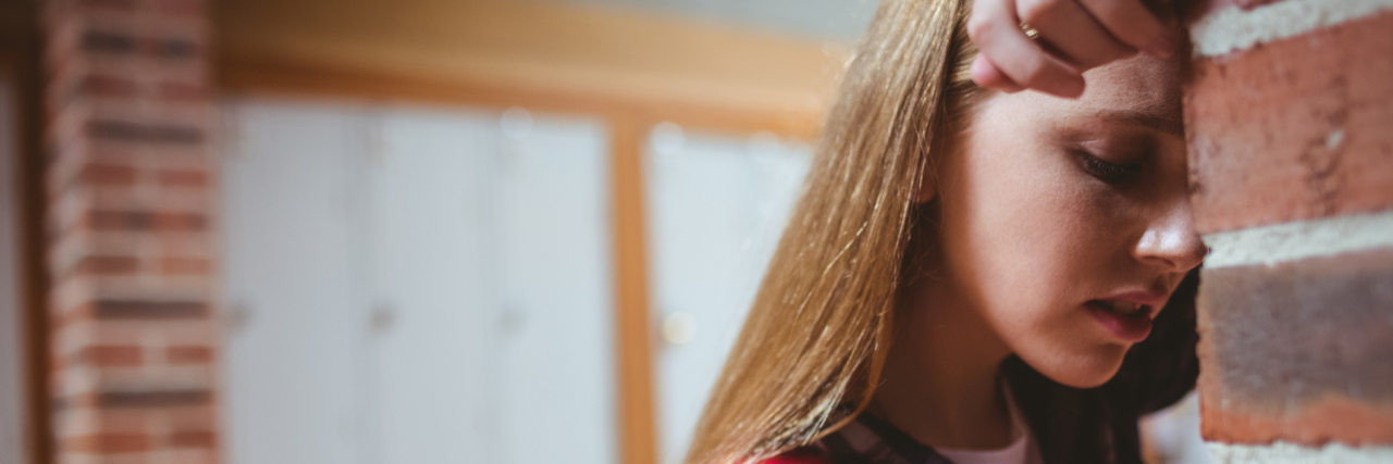 Advice for the Kid in High School With Social Anxiety worried upset female student leaning head against wall