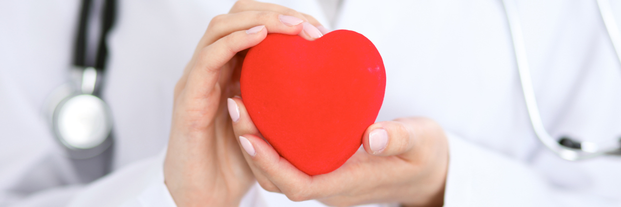 The Importance of Having a Compassionate Medical Team A doctor holding a red paper heart.