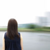 Young woman standing by the river. Blurred background.