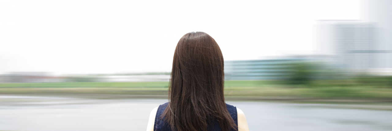 Living With Microcephaly Young woman standing by the river. Blurred background.
