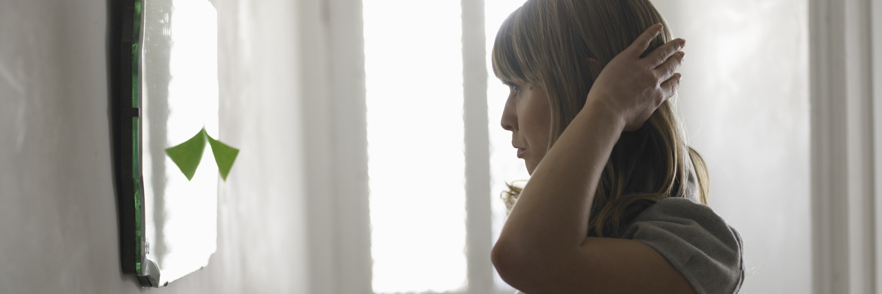 Effects of Prednisolone for Lupus on Body Image and Self-Esteem woman fixing her hair in a hallway mirror