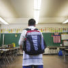 Boy wearing backpack in classroom.