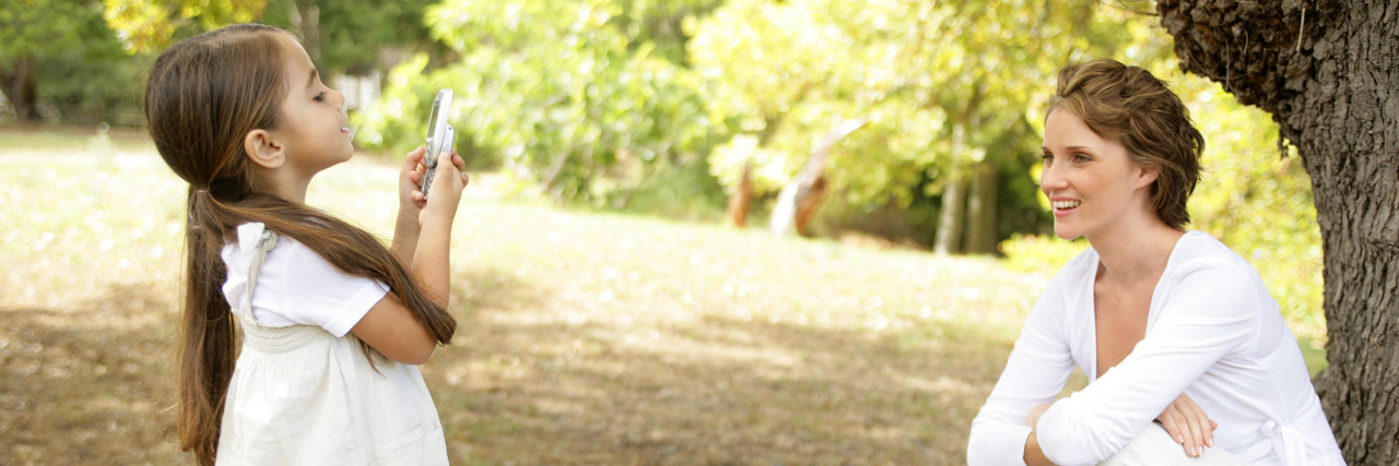 Chronic Illness and Pressure to Look Happy on Social Media Daughter taking picture of mother with cell phone.