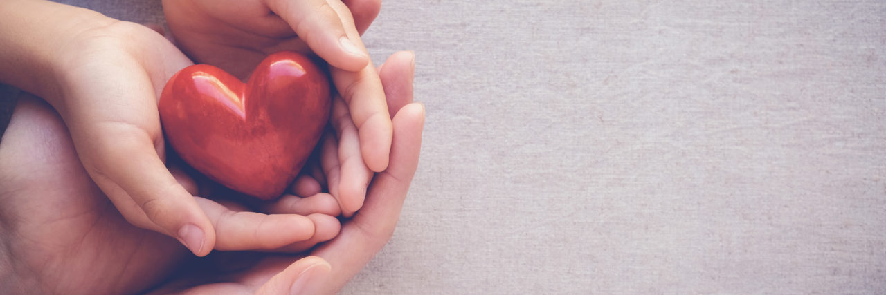 8 Things Child Life Specialists Want You to Know adult and child hands holding red heart, health care love and family concept