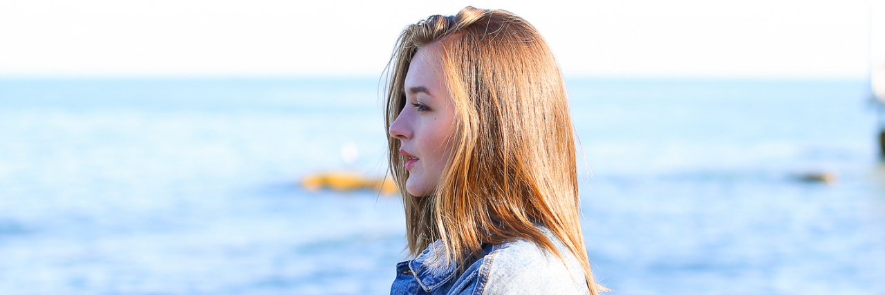 Why I'm Sharing About Life With PCOS and Depression A young woman looking out towards the ocean.