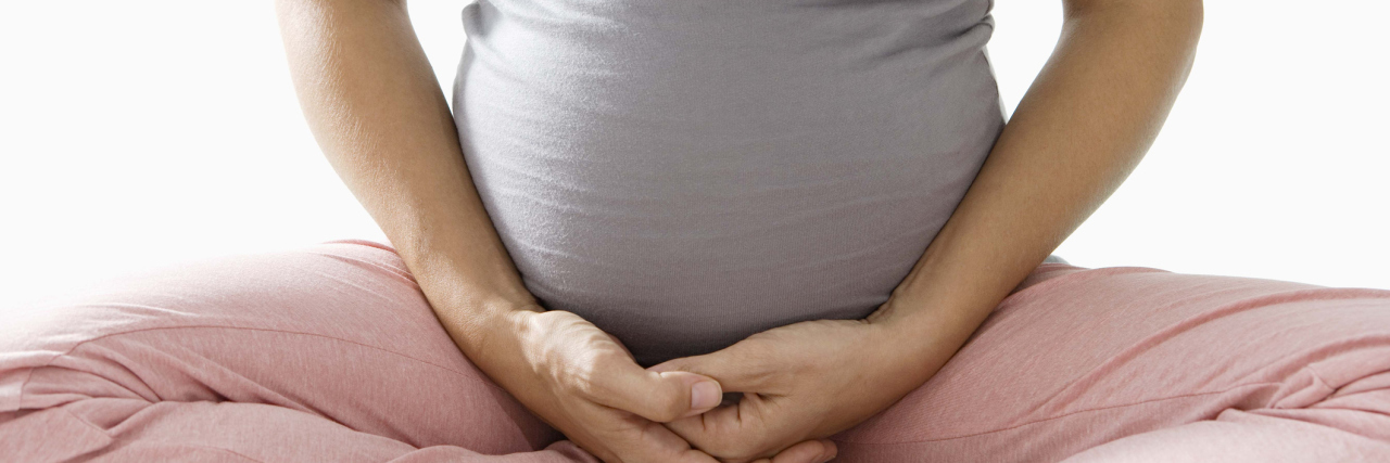 pregnant woman sitting with hands in front of stomach