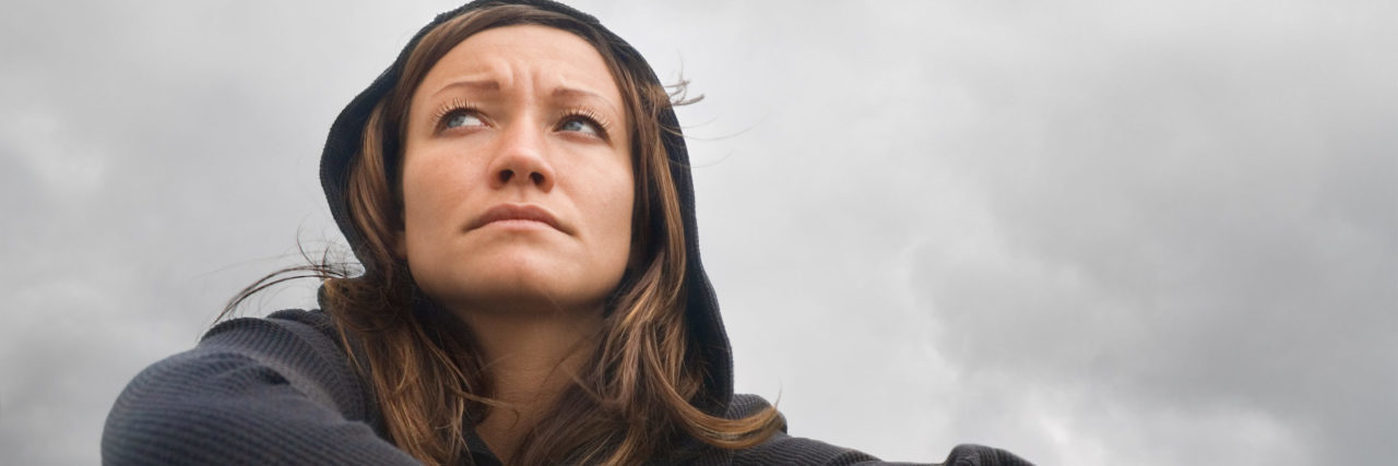 When It Seems Like You Aren't Trying in Depression Recovery low angle shot of woman sitting with arms crossed on cloudy day looking sad or contemplative