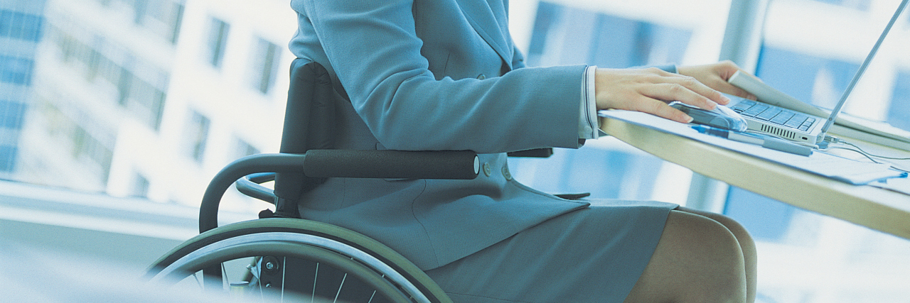 Businesswoman sitting at desk in a wheelchair.