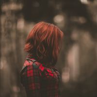 woman with red hair stands in the forest