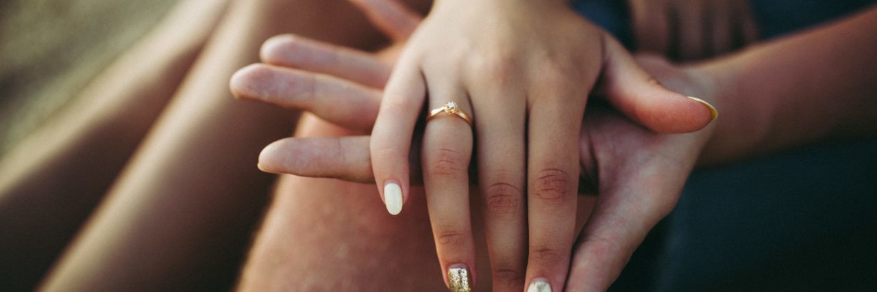married couple holding hands with focus on ring on woman's ring finger