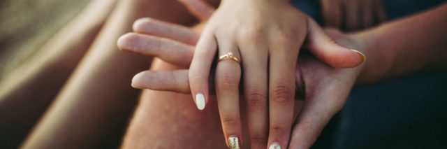 married couple holding hands with focus on ring on woman's ring finger