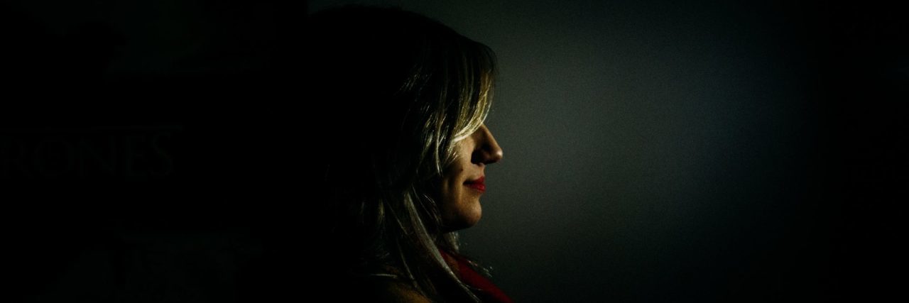 woman partially obscured in darkness with only face visible in profile