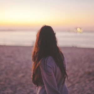 woman standing on a beach looking at sunset