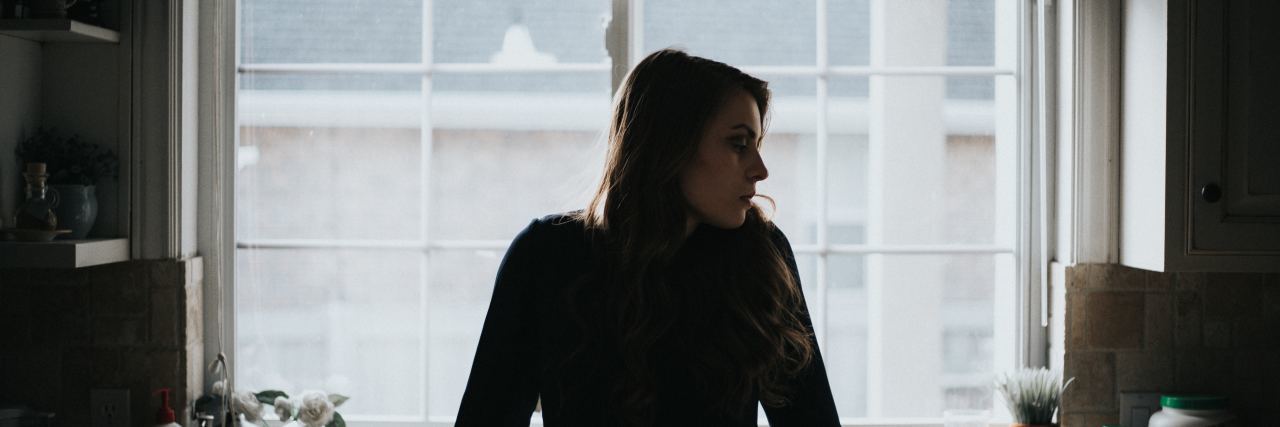 To the Depression That Made Me Who I Am Today a woman stands in her kitchen looking to the side