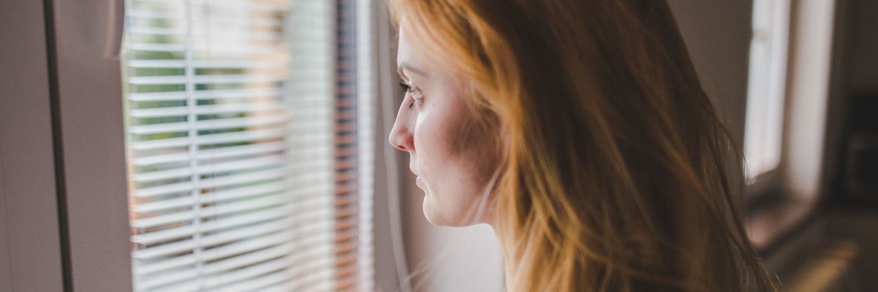 When Anxiety Makes You Compare Yourself to Others woman with long red hair looks out the window