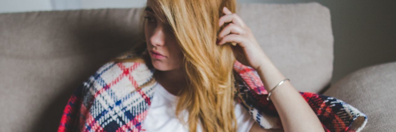 young woman sitting in chair looking depressed and away from camera