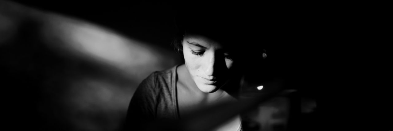 woman in black and white. face illuminated by light coming in from window