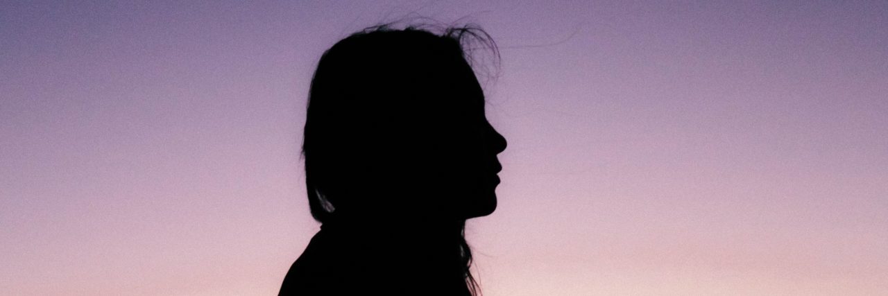 silhouetted woman against sunset sky