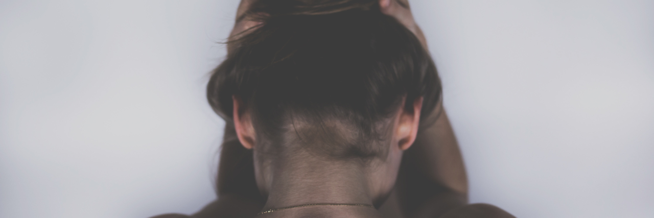 Scoliosis Is a Painful Condition The writer facing a wall, showing the top of her spine.