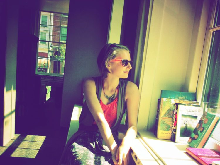 woman wearing sunglasses and looking out a window