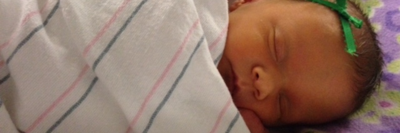 Getting My Daughter's Diagnosis Was a Whirlwind of Emotions Baby girl in the hospital wrapped in a blanket.