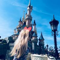 young blonde woman at disneyland looking at magic kingdom castle